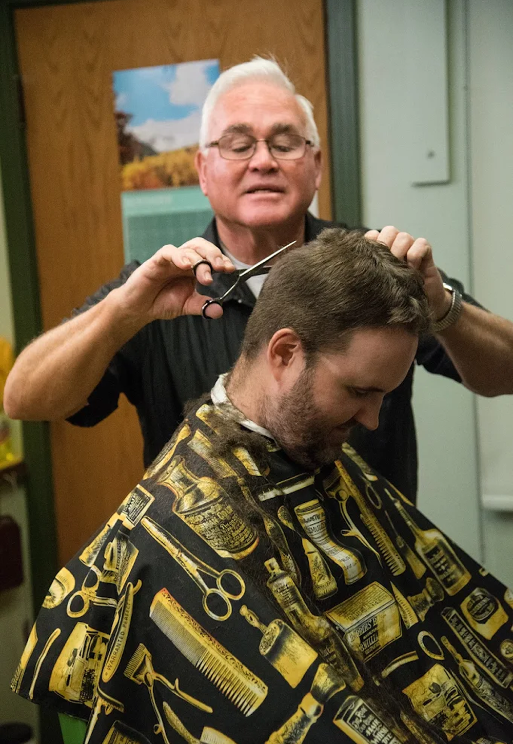 Image of Lin cutting a mans hair with scissors